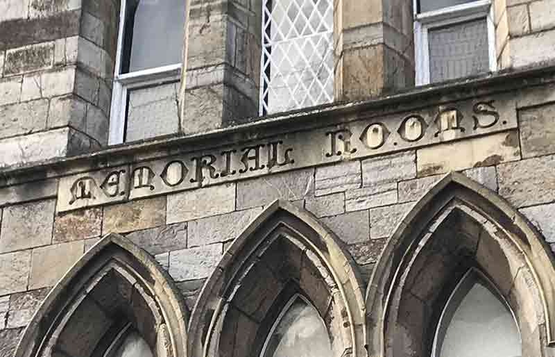 Carved stone sign above three arched windows.
